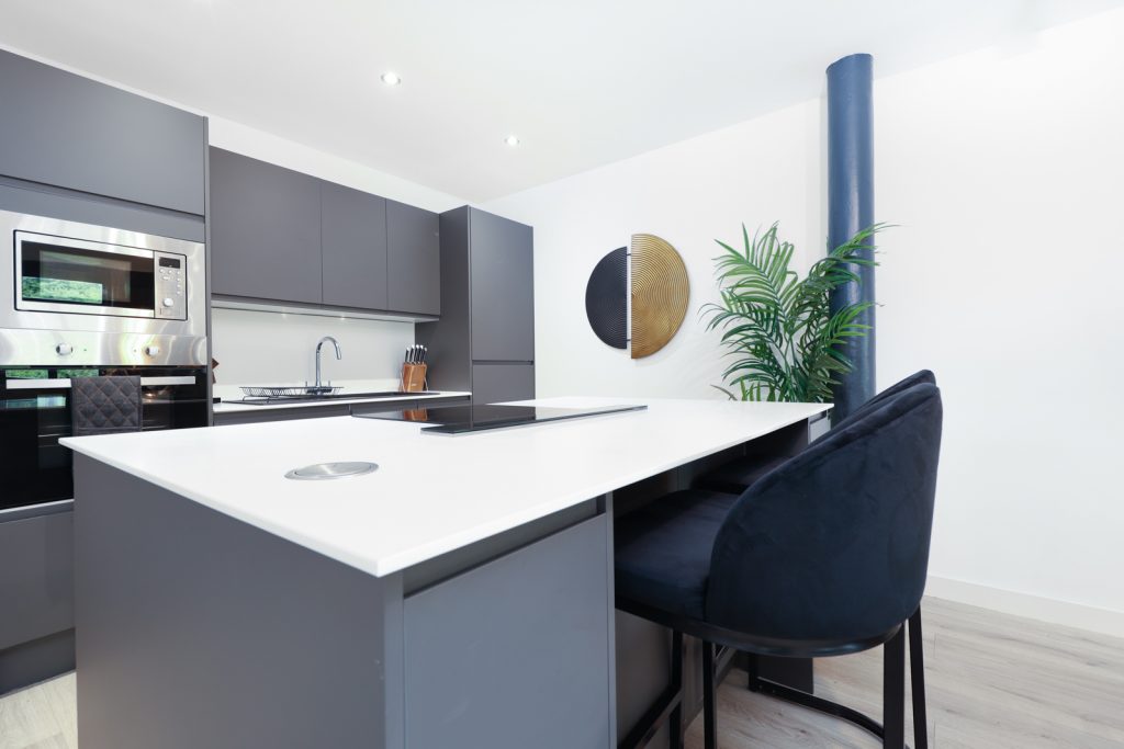 Modern grey kitchen with blue stools and artwork