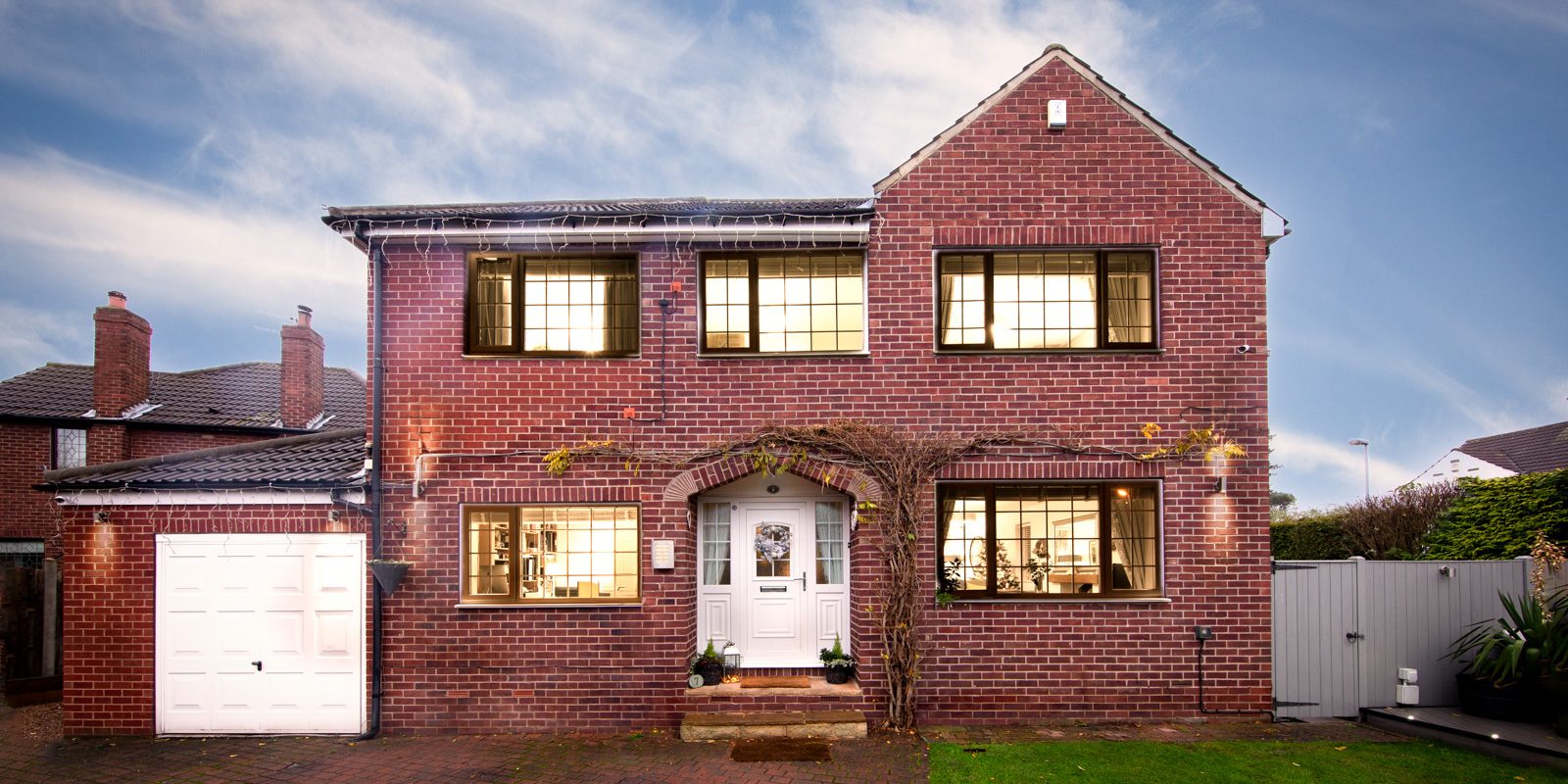 red-brick-house-lights red brick house with lights on showing garden and drive